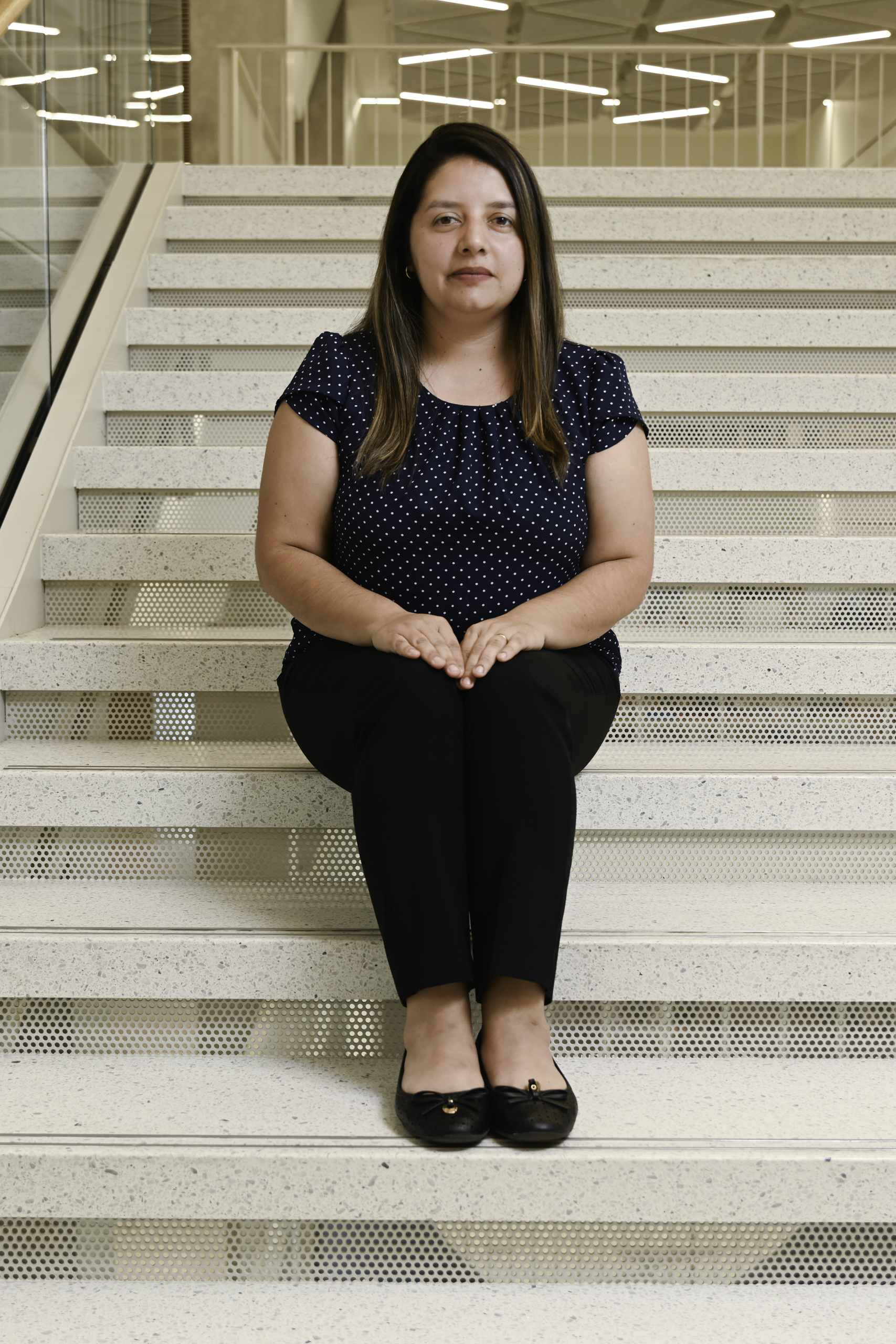 Laura Cruz Castro sitting on the steps connecting the 4th and 5th floors of the Malachowsky building at UF.